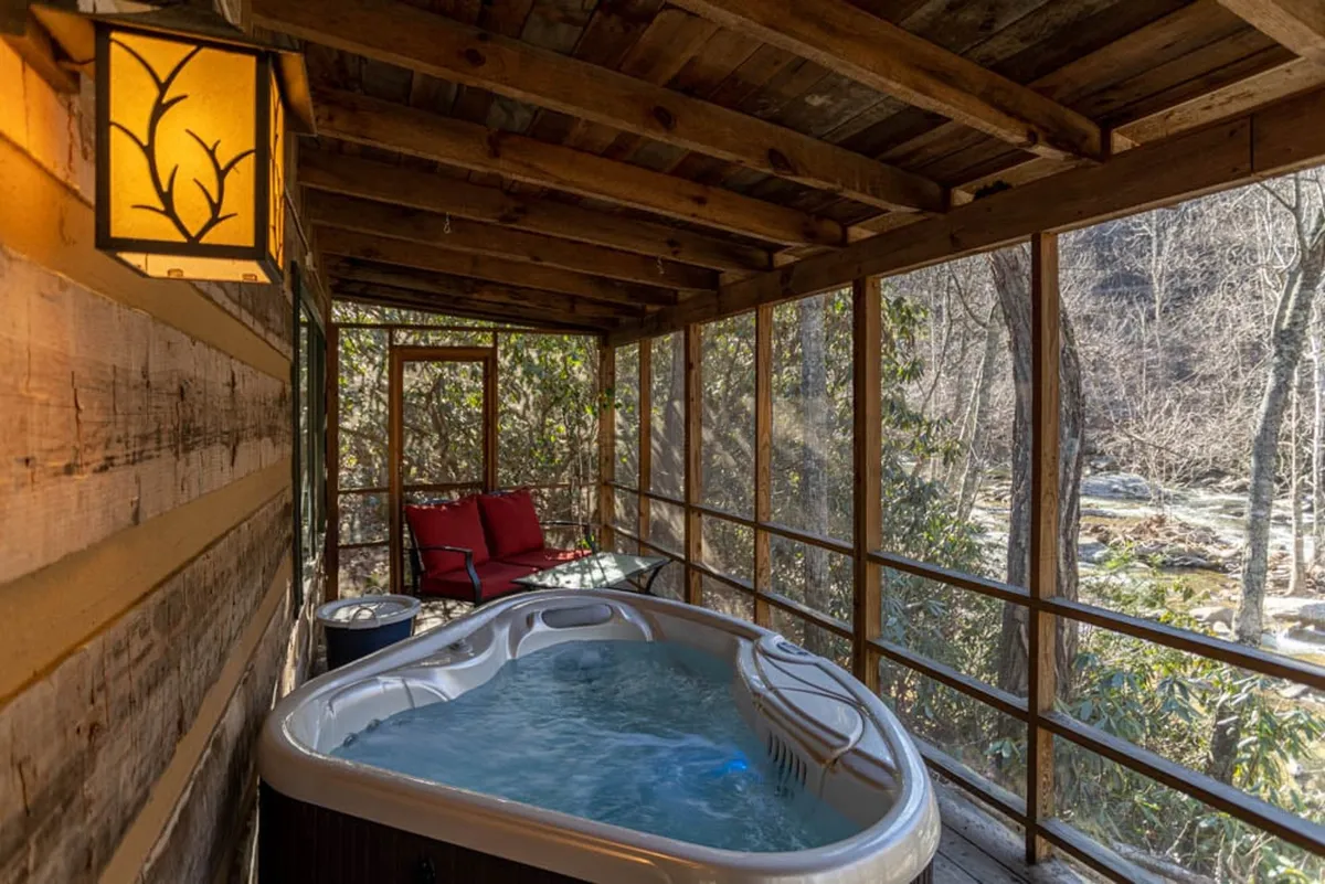 This image showcases a tranquil hot tub area indoors, accented with wooden beams and red chairs, offering a peaceful place to unwind. Through the windows, one can see glimpses of the surrounding landscape, subtly linking the interior comfort with the outdoor environment and seasonal relaxation.